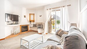 A modern living room with a fireplace, a sofa set, a television, and a sliding glass door leading to an outdoor area. - Recently Renovated Ground Floor Apartment, 2 new Bathrooms with walk in showers  (Albufeira, Faro)