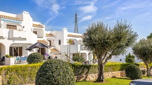 A white building with balconies, a patio area with outdoor furniture, and a well-maintained garden with trees and shrubs. - Recently Renovated Ground Floor Apartment, 2 new Bathrooms with walk in showers  (Albufeira, Faro)