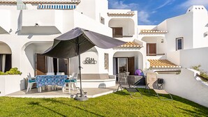 A white building with a sign reading "Casa Dowle" and a patio area with a table, chairs, and an umbrella. - Recently Renovated Ground Floor Apartment, 2 new Bathrooms with walk in showers  (Albufeira, Faro)