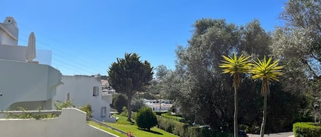 Ein weißes Gebäude mit geneigtem Dach, umgeben von gepflegter Bepflanzung und blauem Himmel.