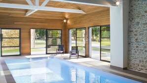 Una piscina interior con vigas de madera y paredes de piedra.