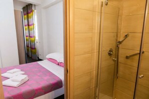 A hotel room with a bed, a shower, and a bathroom door. - Apartment Giusy - central (SORRENTO)