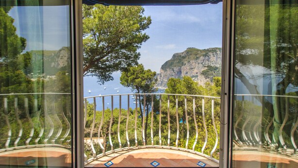 A balcony with a view of a coastal landscape, including trees and cliffs. - Villa with wonderful panoramic sea view with private pool (Capri)