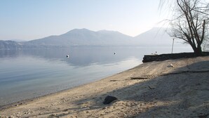 Une plage bordée d’un rivage rocheux, avec une eau calme et des montagnes en arrière-plan.