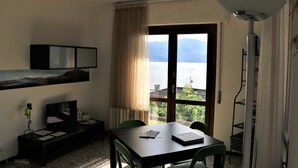 Une chambre d’hôtel équipée d’une table à manger, de chaises, d’un téléviseur, d’une bibliothèque et offrant une vue sur la mer.