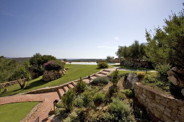 Un jardin aménagé avec une piscine, des murs en pierre et une vue dégagée sur le paysage environnant.