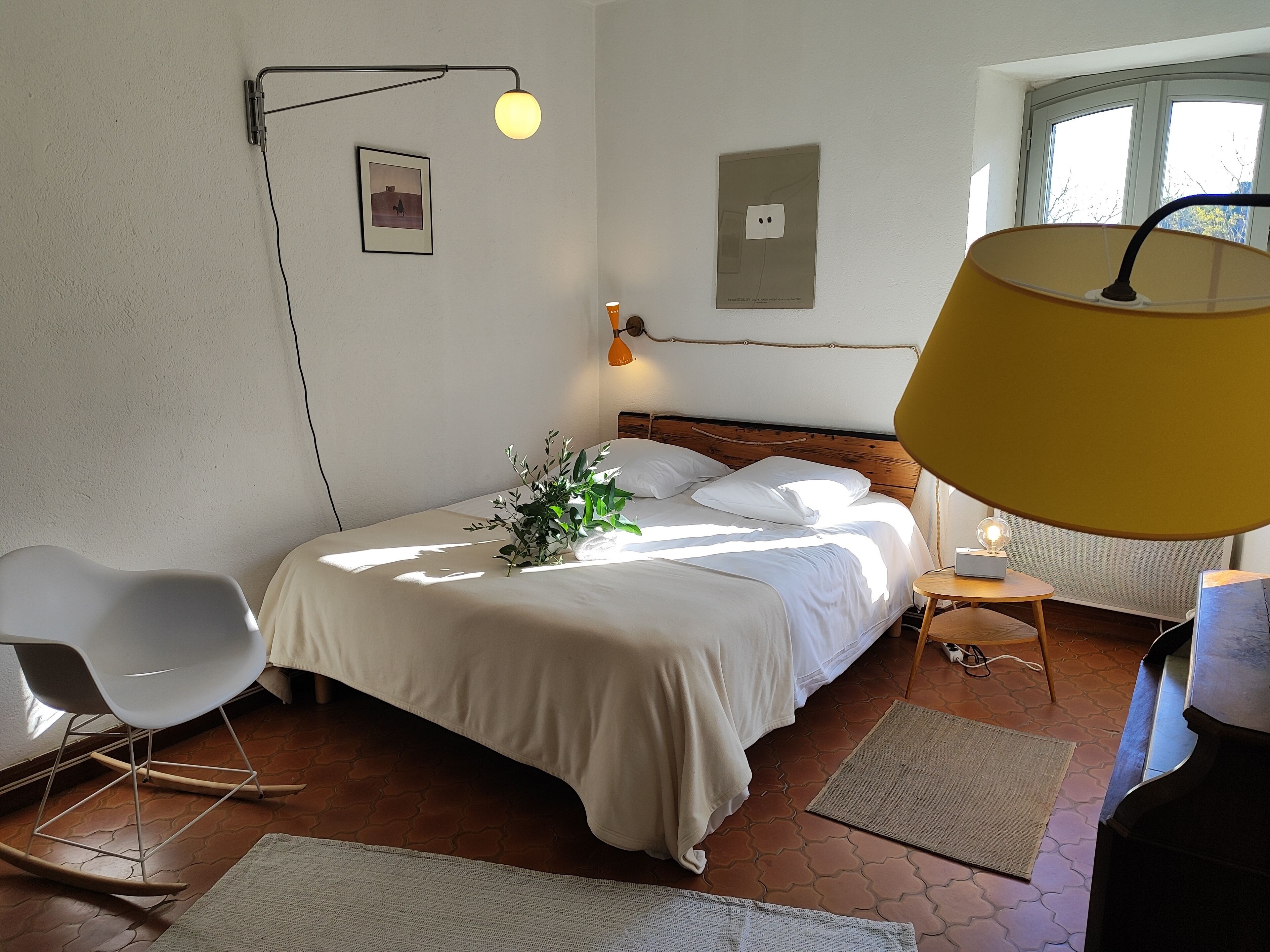 Una camera da letto con un letto, una sedia, una lampada e una finestra.