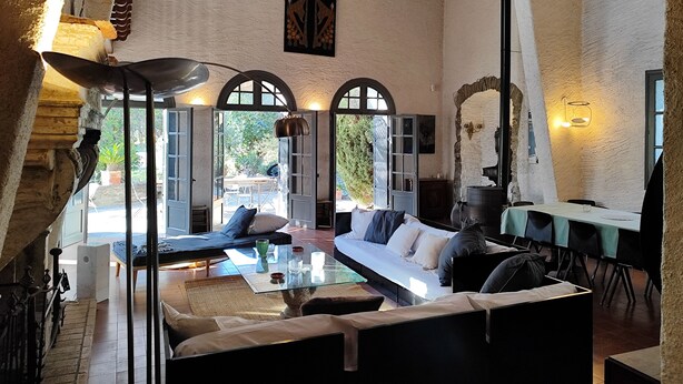 A spacious living area with a large sofa, a glass coffee table, and a fireplace. There are multiple windows and doors providing natural light and views. - Mansion - Port -vendres (Port-Vendres)