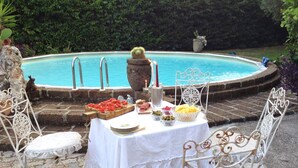 An outdoor dining setup with a pool in the background. - La Bouganville swimming pool & relaxation (Camaiore)