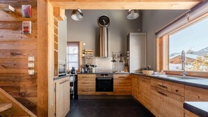 Une cuisine moderne avec des meubles en bois, un four encastré et une grande fenêtre donnant sur l’extérieur.