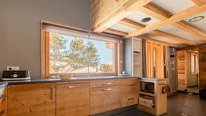 Une cuisine moderne avec des meubles en bois, une grande fenêtre et une vue sur les arbres.