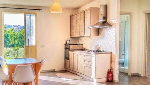 Una cocina moderna con una isla central, un área de comedor con mesa y sillas, y vista a zonas verdes.