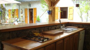Una cucina con mobili in legno, un fornello a gas, un lavello e un muro in pietra.