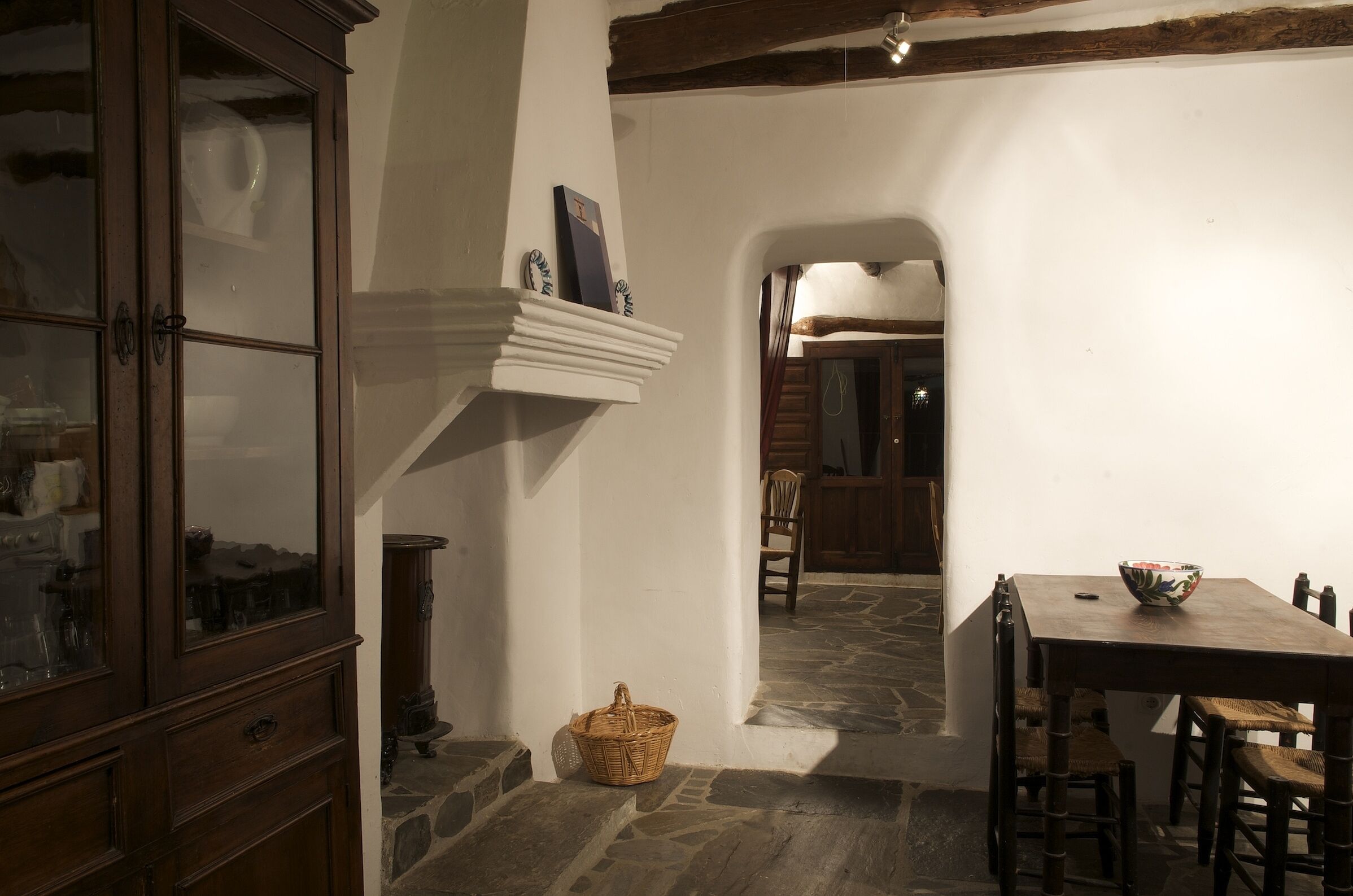 A dining area with a stone floor, wooden furniture, and a basket on the floor.