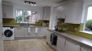 A modern kitchen with a washing machine, a stove, and a window with a view of greenery.