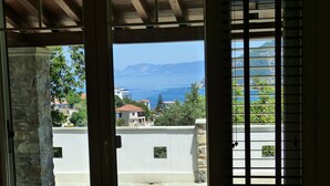 Blick von einem Balkon mit Steinböden, einer weißen Wand und einer Holzbalkendecke.