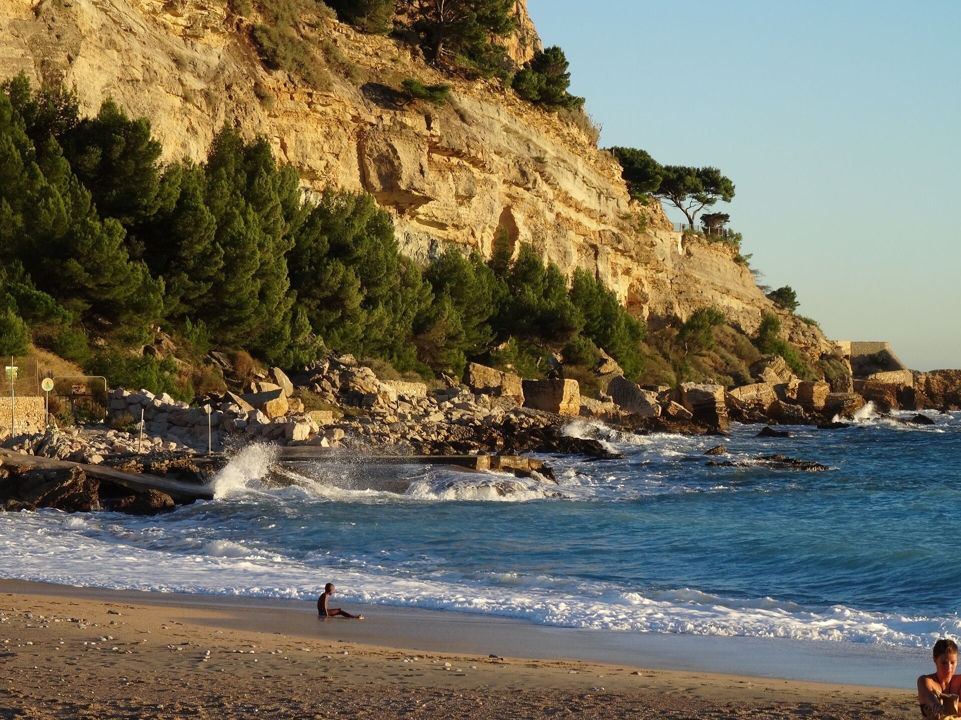 Una playa con acantilados rocosos y olas rompiendo en la orilla.