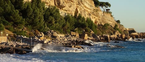 A beach with rocky cliffs and waves crashing onto the shore.