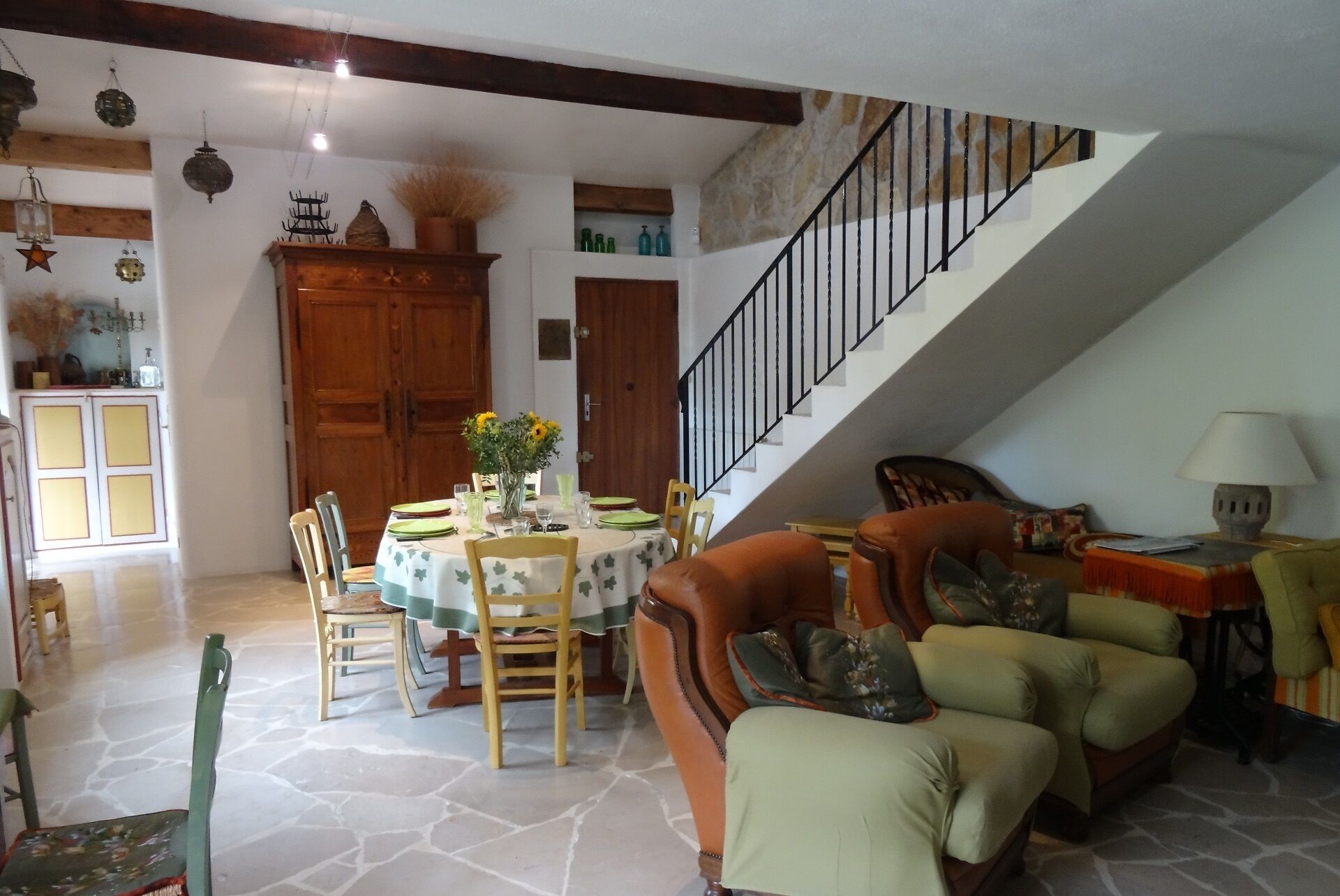 A dining area with a round table, chairs, and a staircase leading to an upper level.