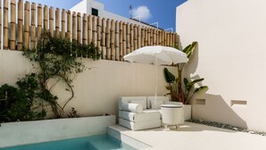 Ein moderner Außenpoolbereich mit einer weißen Couch und einem Tisch unter einem weißen Sonnenschirm.