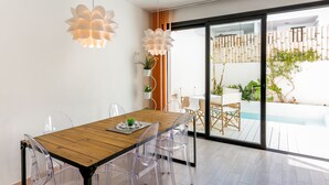 Ein moderner Essbereich mit Holztisch, klaren Stühlen und zwei hängenden Pendelleuchten.