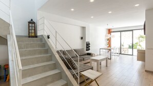 Ein modernes Wohnzimmer mit Treppe, einer Couch, einem Couchtisch und einem Essbereich.
