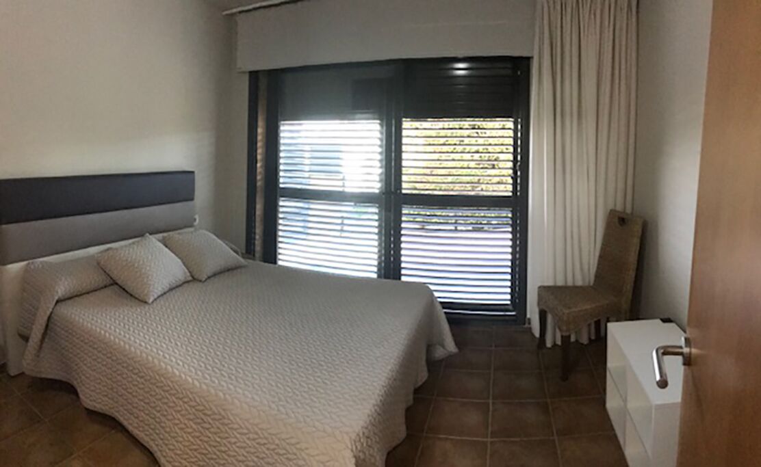 Une chambre d’hôtel avec un lit, une chaise, une fenêtre avec des stores et un lavabo.