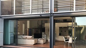 Una casa moderna con un ventanal que da a una sala de estar con sofá y televisor.