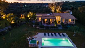 Eine Villa mit Pool, Sitzgelegenheit im Freien und einem gepflegten Garten.