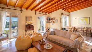 Ein gemütliches Wohnzimmer mit Holzbalkendecke, einer Couch, einem Couchtisch und einem Bücherregal.