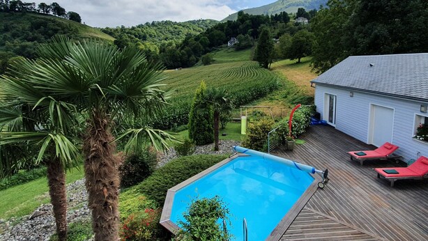 A pool area with lounge chairs, a wooden deck, and a view of a vineyard and hills in the background. - Great architect Villa with swimming pool (Ossen)