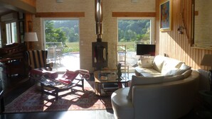 A living room with a fireplace, a sofa, a TV, and a view of the outdoors. - Great architect Villa with swimming pool (Ossen)