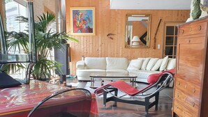 A living room with a wooden floor, a white sofa, a glass coffee table, and a red-striped tablecloth. - Great architect Villa with swimming pool (Ossen)