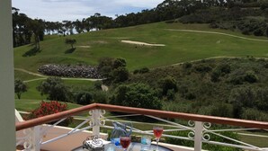 Un balcon avec une table dressée pour deux personnes, donnant sur un terrain de golf.
