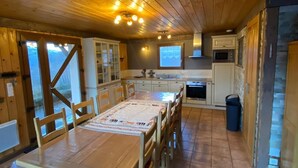 Un interior de madera con una mesa de comedor, sillas, una zona de cocina y un ventanal grande.