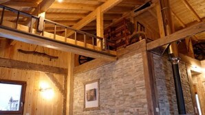 Un interior de madera con pared de piedra, escalera de madera y chimenea.