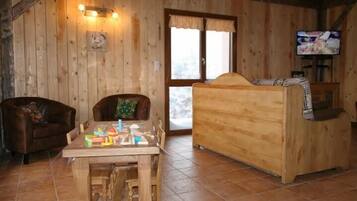 Cozy cabin-style room with a wooden table, leather sofa, and large window offering a view of the outdoors.