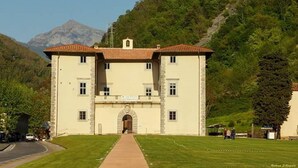 Ein großes, zweistöckiges Gebäude mit einer symmetrischen Fassade, einem zentralen Eingang mit Bogen und einem Ziegeldach.