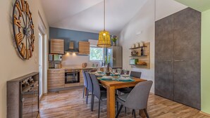 A modern kitchen with wooden cabinets, a built-in oven, and a dining area with a wooden table and chairs.