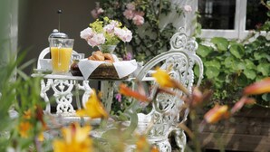 A white ornate chair with a basket of croissants and a glass of orange juice on a table. - Just So Cottage (Buckingham)