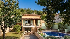 Une maison à deux étages avec une piscine, un espace salon extérieur et une statue de Bouddha.