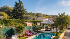 Une piscine avec des chaises longues, un gazebo et une vue sur les maisons au loin.
