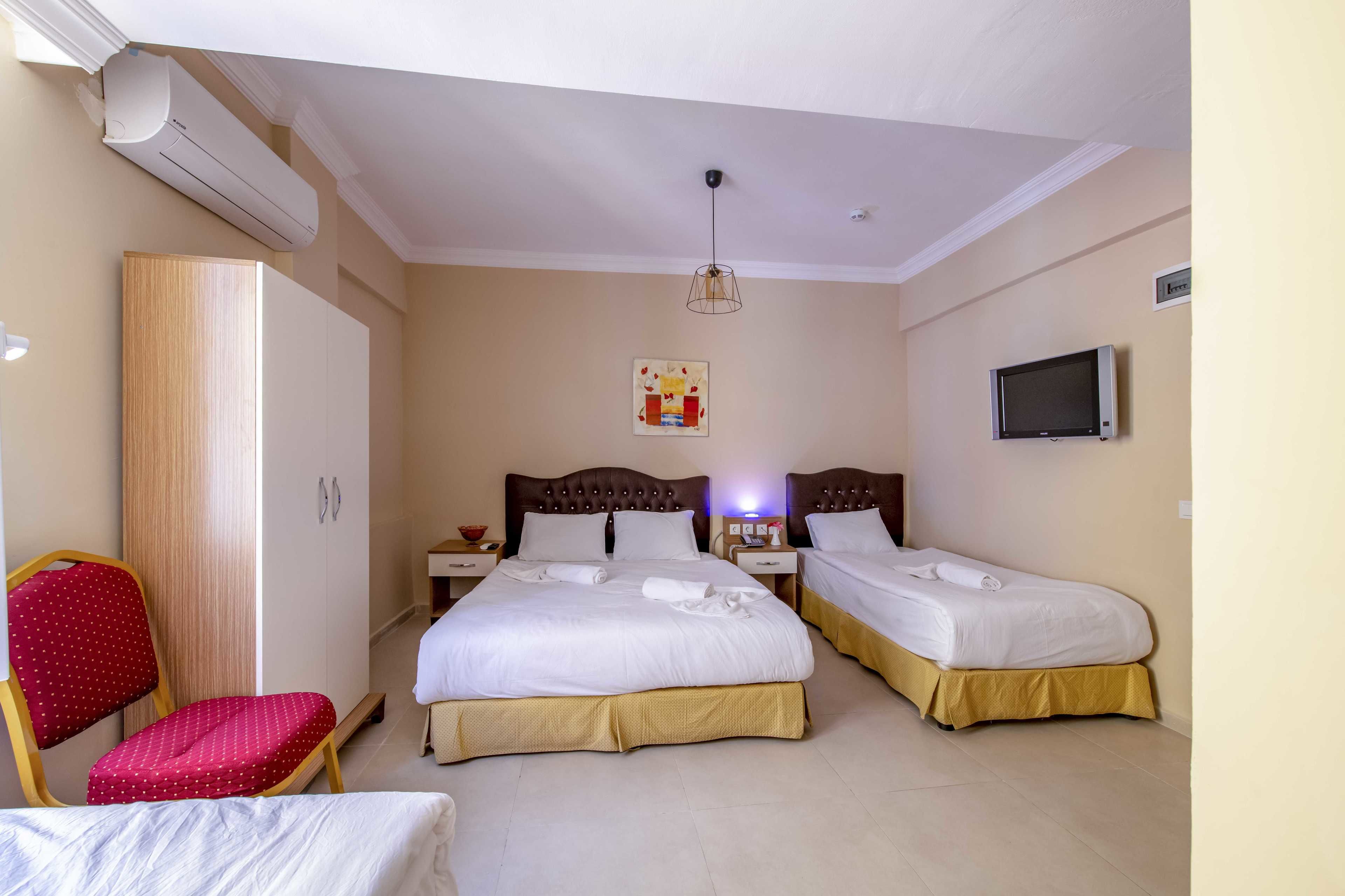 Habitación de hotel con dos camas, un armario, una silla, un televisor y un aire acondicionado.