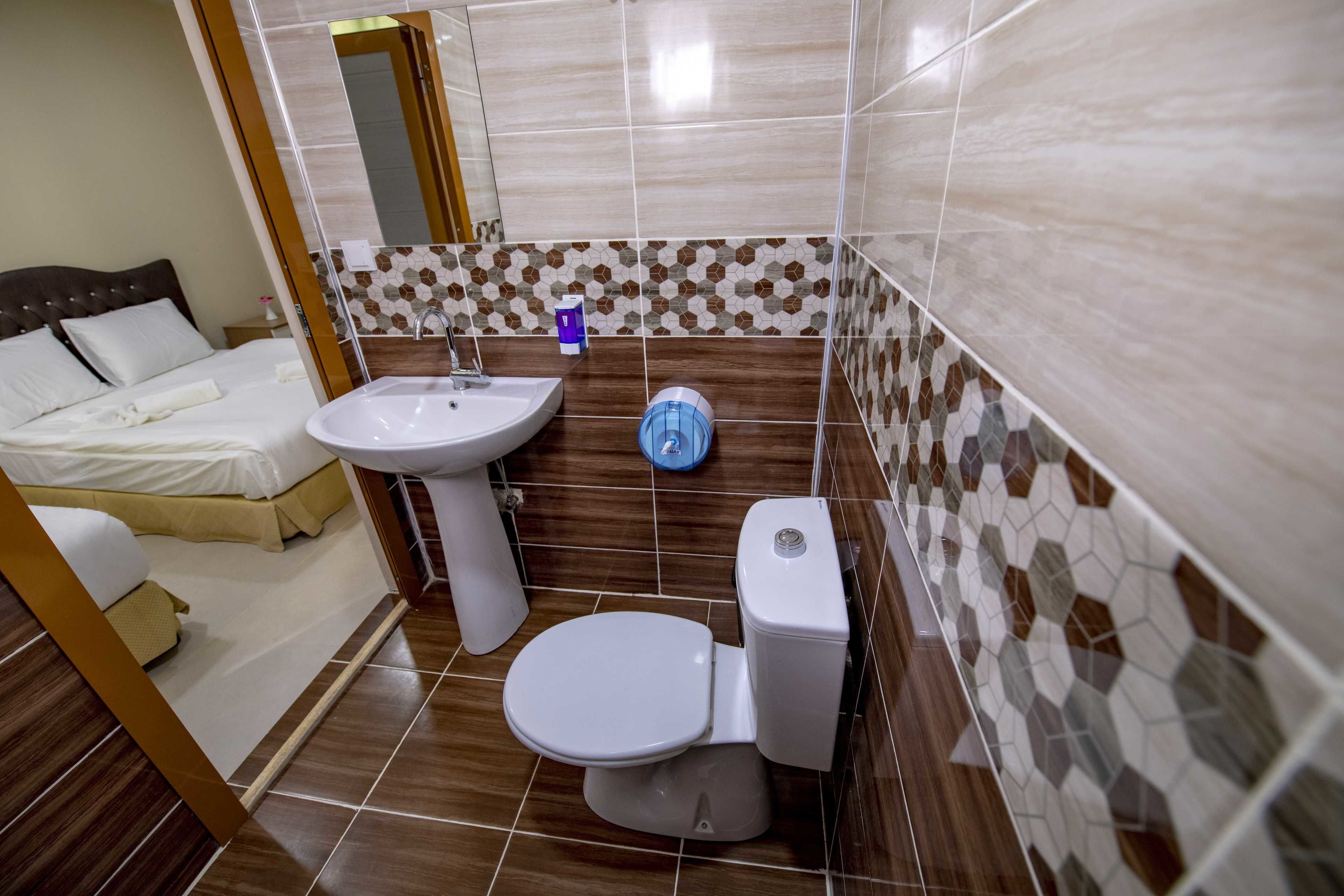 A bathroom with a toilet, sink, and mirror.