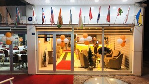 L’entrée d’un hôtel, avec des drapeaux, un espace d’accueil et une porte en verre.