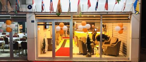 A hotel entrance with flags, a reception area, and a glass door.