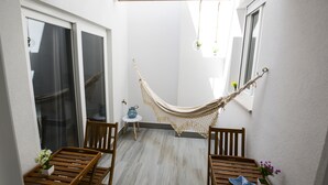 Un petit patio abrité, doté d’un hamac, de meubles en bois et de plantes en pot.