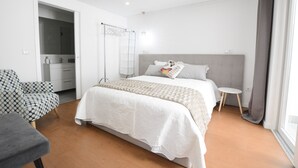 Une chambre moderne avec un grand lit, une table de chevet, une chaise et un dressing.