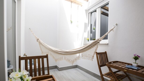 Une pièce avec un hamac, des meubles en bois et une petite table sur laquelle est posée une plante.