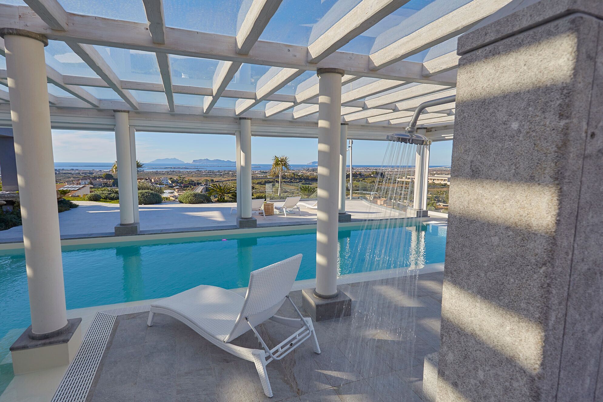 An infinity pool with a white chair and a water feature.